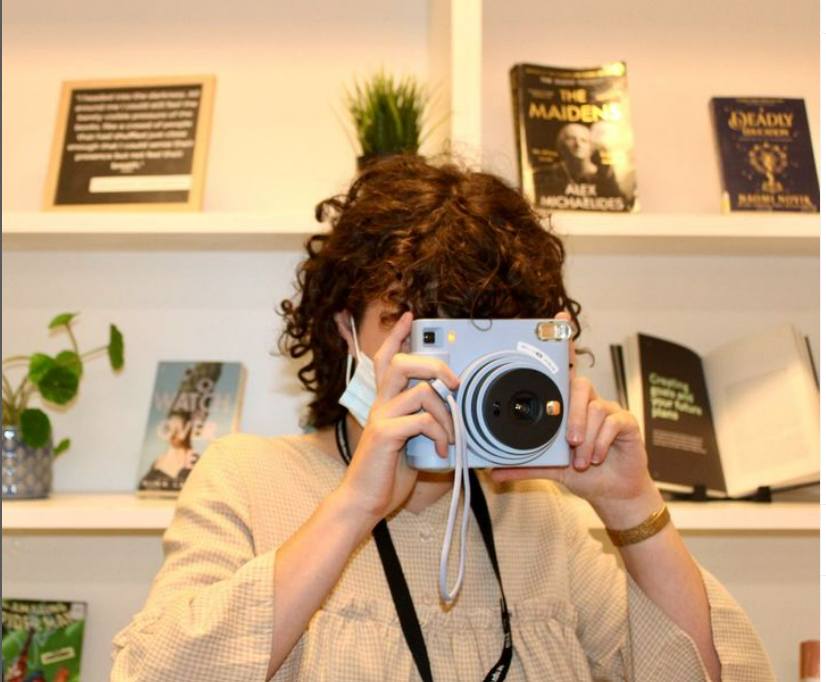 Person taking photo with a blue polaroid camera